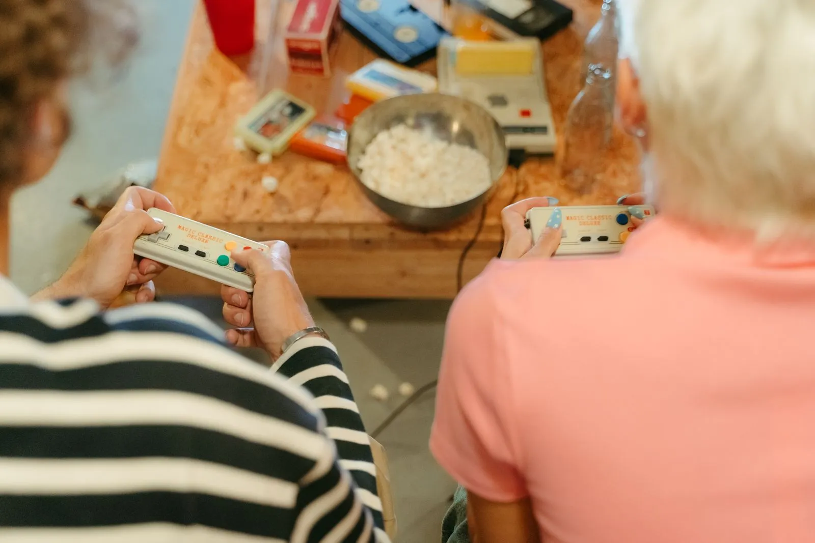 Two teenagers play video games together with snacks, creating a fun indoor atmosphere.